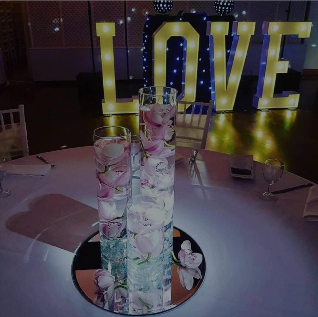 Light-up LOVE letters behind a wedding table centrepiece